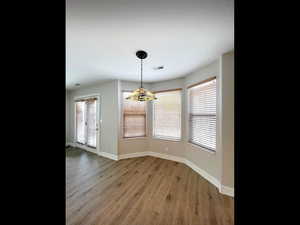 Unfurnished dining area with visible vents, baseboards, an inviting chandelier, and light wood-style floors