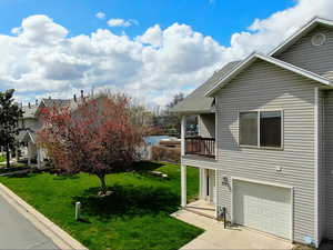 View of side of property with an attached garage, a shingled roof, driveway, and a lawn