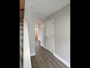 Corridor featuring wood finished floors, baseboards, and stairs