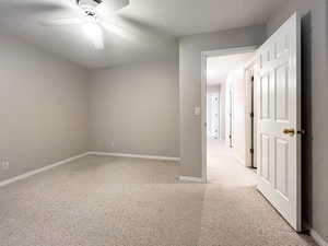 Empty room with light colored carpet, baseboards, and a ceiling fan