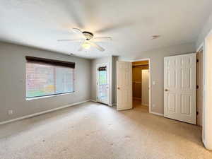 Unfurnished bedroom featuring access to outside, baseboards, light carpet, a textured ceiling, and ceiling fan