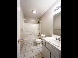 Full bathroom featuring washtub / shower combination, toilet, a textured ceiling, vanity, and tile patterned floors