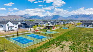 View of basketball court featuring a lawn, a residential view, fence, a mountain view, and a tennis court