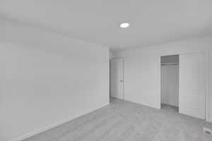 Unfurnished bedroom featuring light carpet and a closet