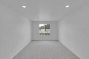 Empty room with light carpet and recessed lighting
