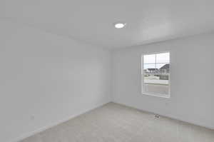 Spare room with light carpet and baseboards