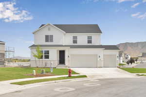 Traditional-style house featuring a mountain view, driveway, a garage, a front yard, and a shingled roof