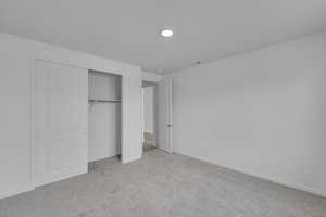 Unfurnished bedroom with light colored carpet and a closet