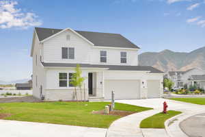 Traditional-style home featuring a mountain view, a front yard, stone siding, concrete driveway, and a garage