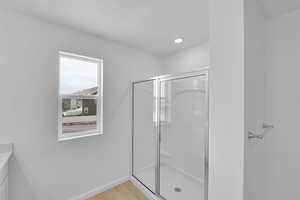 Full bathroom with a stall shower, vanity, light wood-style floors, and recessed lighting