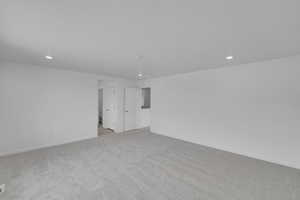 Empty room with light colored carpet and recessed lighting