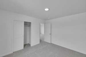 Unfurnished bedroom with light colored carpet and a closet