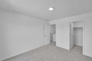 Unfurnished bedroom with a walk in closet and light colored carpet