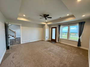 Unfurnished bedroom featuring a raised ceiling, carpet flooring, recessed lighting, access to exterior, and ceiling fan