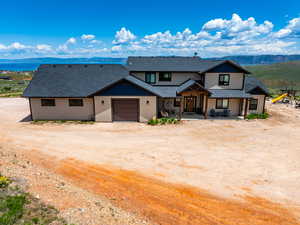 View of front facade with driveway, a shingled roof, a garage, a mountain view, and a porch