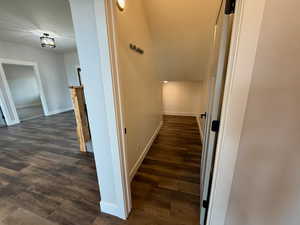 Corridor featuring baseboards and dark wood-type flooring