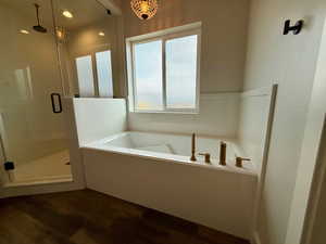Bathroom featuring a shower stall, a bath, and dark wood-style flooring