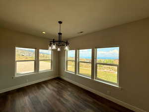 Unfurnished dining area featuring a chandelier, dark wood-type flooring, and recessed lighting