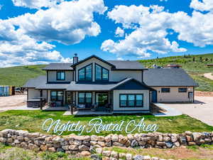 Back of house featuring a hot tub, a patio, roof with shingles, and a lawn