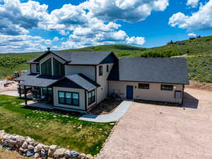 View of front of property with a shingled roof, cooling unit, board and batten siding, a patio area, and a front yard