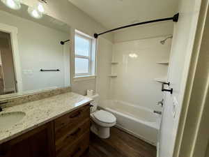 Bathroom featuring tub / shower combination, vanity, and dark wood-type flooring