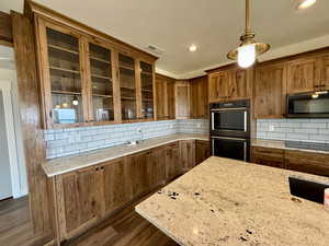 Kitchen featuring brown cabinets, tasteful backsplash, glass insert cabinets, dark wood-style floors, and recessed lighting