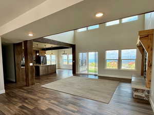 Unfurnished living room with healthy amount of natural light, a high ceiling, dark wood finished floors, and recessed lighting
