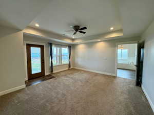 Unfurnished room with carpet floors, a raised ceiling, a ceiling fan, and recessed lighting