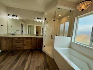 Bathroom featuring a stall shower, double vanity, a garden tub, and dark wood-type flooring