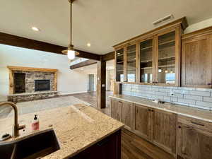 Kitchen with dark wood-style flooring, glass insert cabinets, beam ceiling, decorative backsplash, and open floor plan