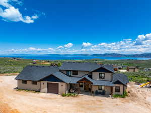 View of front facade featuring roof with shingles, a garage, driveway, a porch, and a water and mountain view