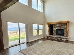 Unfurnished living room with a high ceiling, a fireplace, and dark wood-style flooring