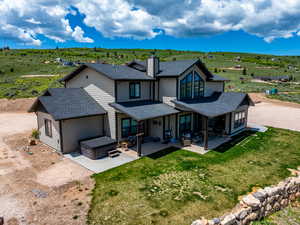 Rear view of property with a hot tub, roof with shingles, a patio area, and a chimney