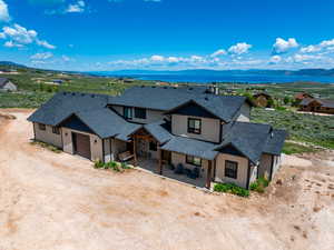 View of front of house with roof with shingles, a garage, a mountain view, dirt driveway, and board and batten siding