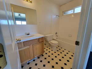 Full bathroom with toilet, tile patterned floors, vanity, and  shower combination