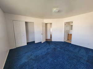 Unfurnished bedroom featuring  a closet, ensuite bath, and carpet flooring