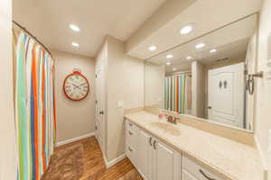 Full bathroom with curtained shower, vanity, light wood-style floors, and recessed lighting