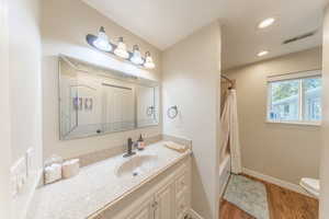 Full bathroom with vanity, light wood-type flooring, shower / tub combo with curtain, and recessed lighting