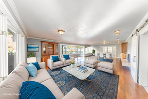 Living area featuring a barn door, light wood-type flooring, ornamental molding, and french doors