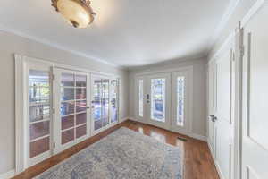 Foyer entrance featuring french doors, dark wood-style floors, crown molding, and a textured ceiling