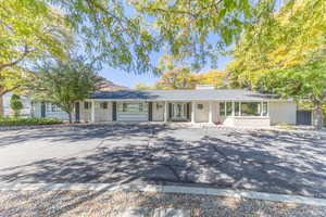 Ranch-style house with brick siding, a chimney, and covered porch