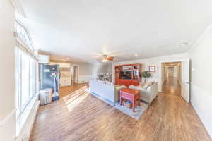 Living room featuring a wainscoted wall, light wood-style floors, ornamental molding, and ceiling fan