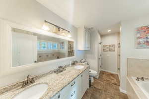Full bathroom featuring a garden tub, double vanity, and recessed lighting