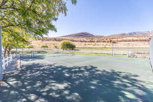 View of tennis court with a rural view and a mountain view