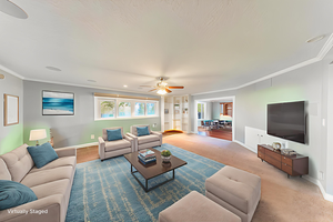 Living area with crown molding, a ceiling fan, and carpet floors