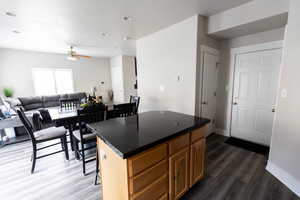 Kitchen with dark wood-type flooring, a center island, baseboards, and ceiling fan