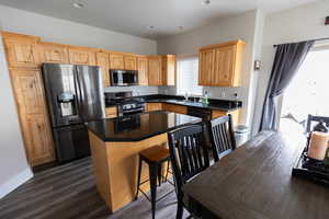 Kitchen featuring recessed lighting, a kitchen island, stainless steel appliances, a breakfast bar area, and dark wood-style floors