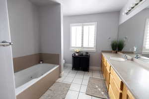 Full bathroom with baseboards, toilet, a tub with jets, vanity, and tile patterned floors