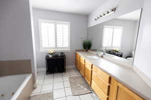 Bathroom with baseboards, toilet, a jetted tub, vanity, and tile patterned flooring