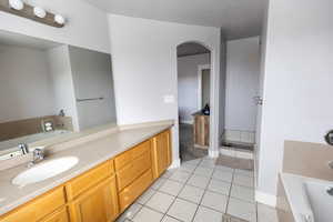 Full bathroom featuring tile patterned floors, vanity, baseboards, and a garden tub